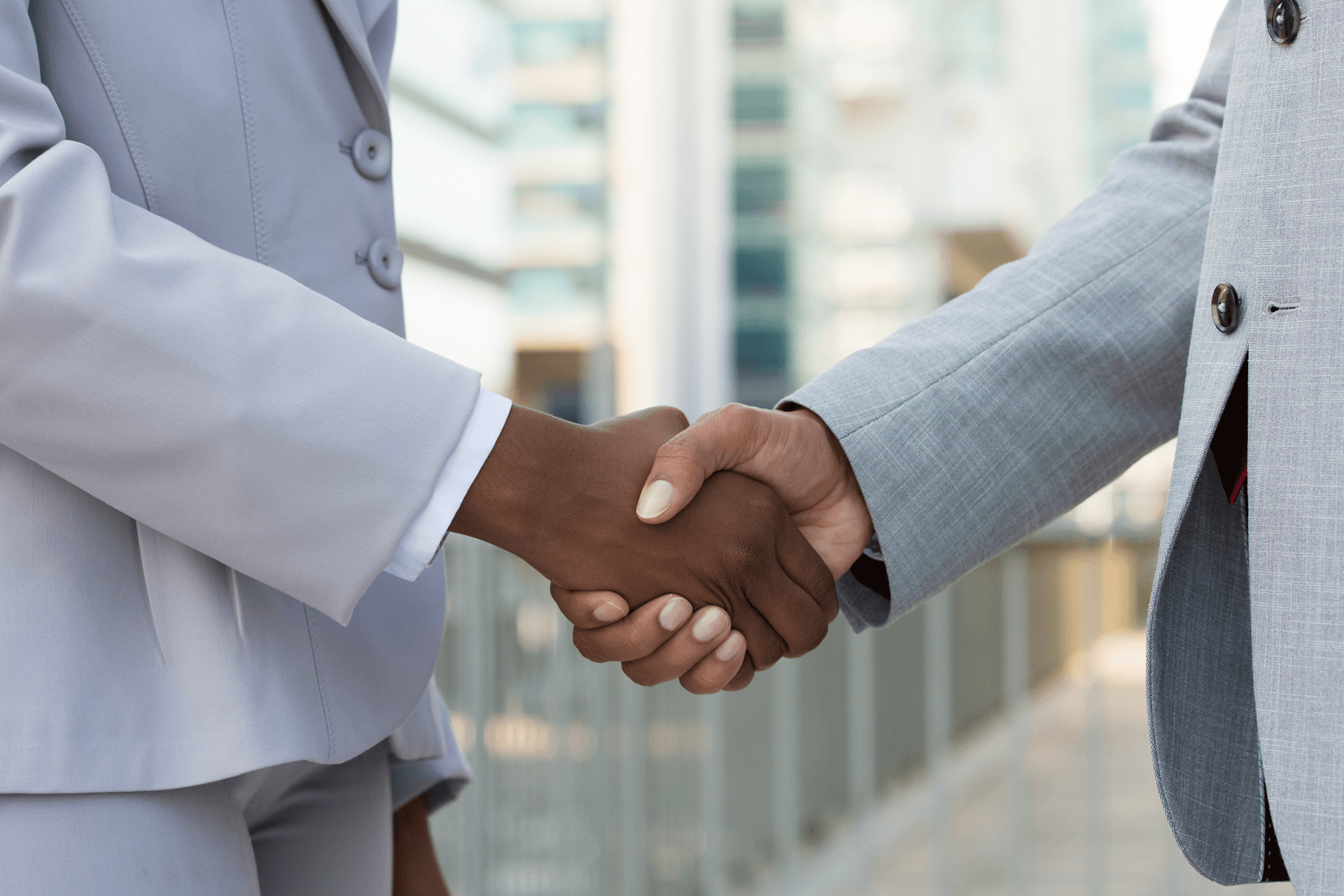 Two professionals shaking hands outside an office building