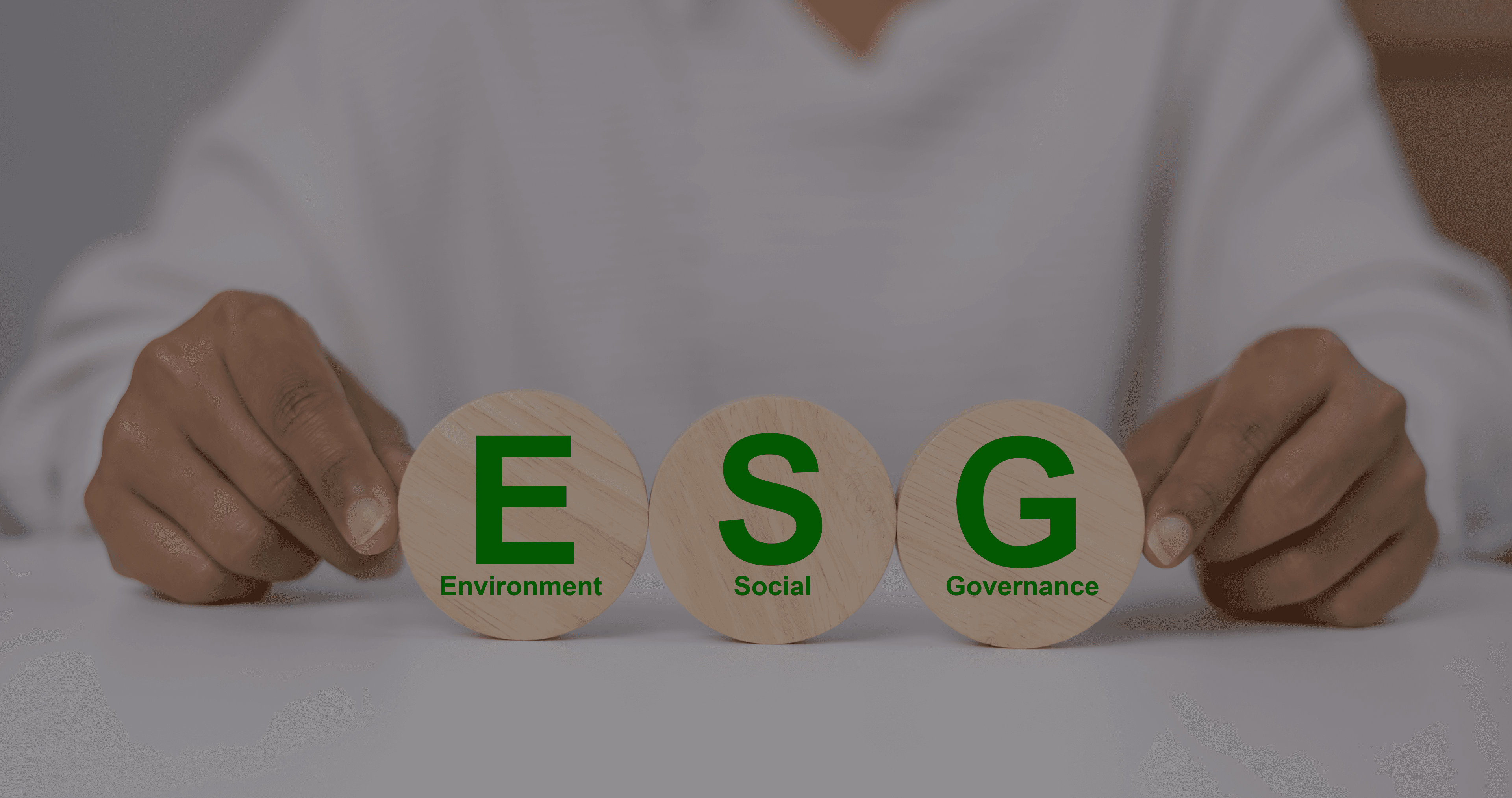 Hands holding wooden discs labelled Environment, Social and Governance